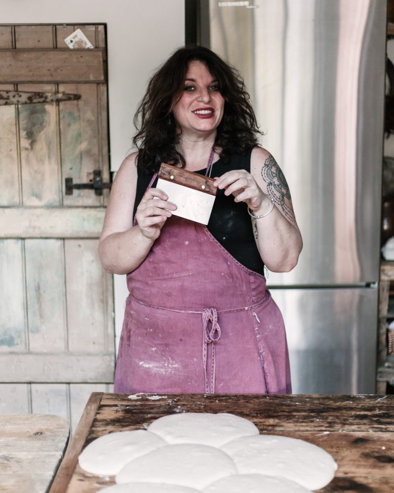 Vanessa holding a scraper and demonstrating essential sourdough baking equipment for beginners.