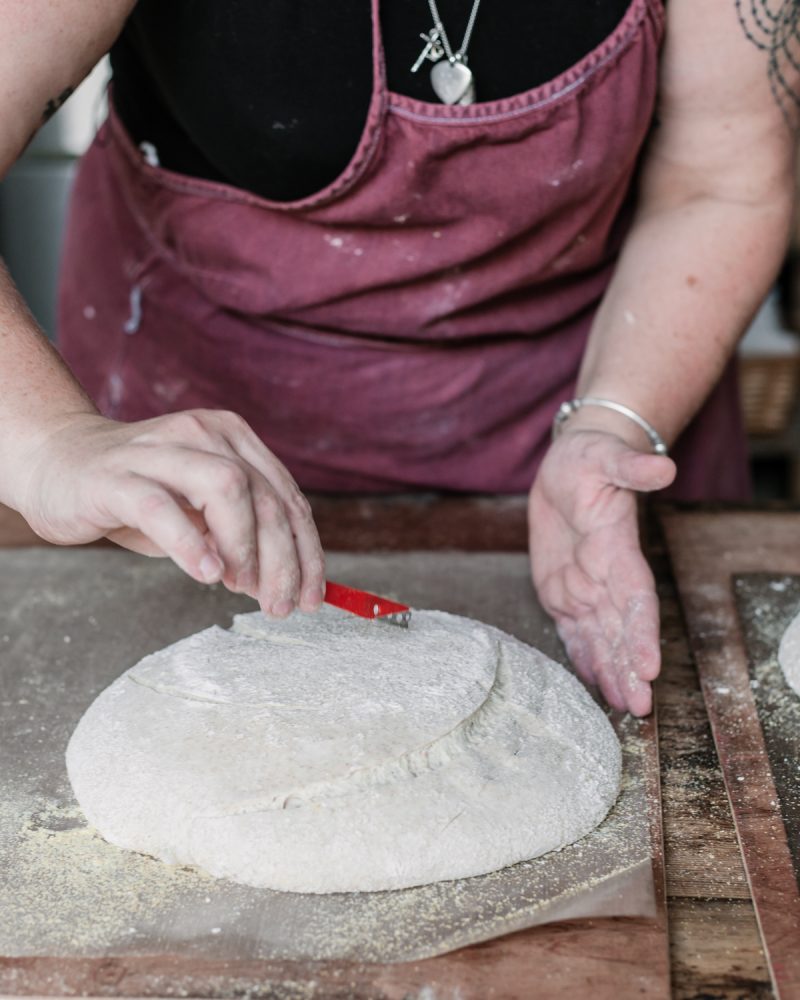 Vanessa scoring bread with a blade  and demonstrating essential sourdough baking equipment for beginners.