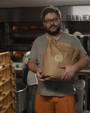 Adam holding 16kg bag of botanical blend flour